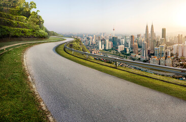 Road with cityscape and skyline in Kuala Lumpur, Malaysia. Sunrise Scene. Logo removed.