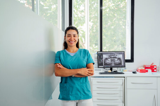 Happy dentist with arms crossed in clinic
