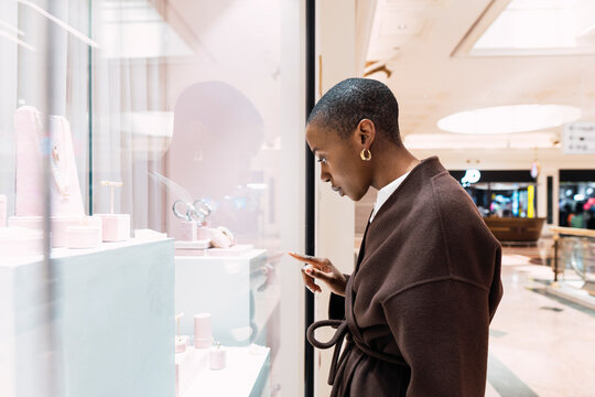 Young woman touching glass of store window