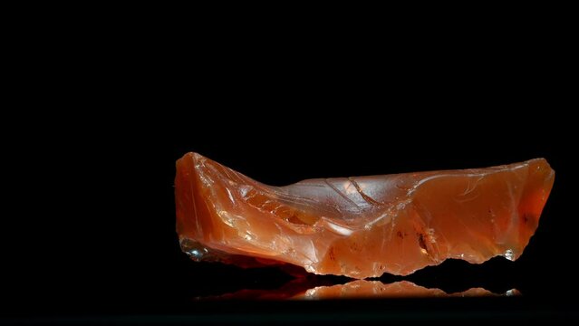 Rough uncut Fire Opal (from Brazil) specimen rotating slowly against a black background.