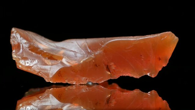 Rough uncut Fire Opal (from Brazil) specimen rotating slowly against a black background.