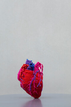 Red woolen heart on table against gray background