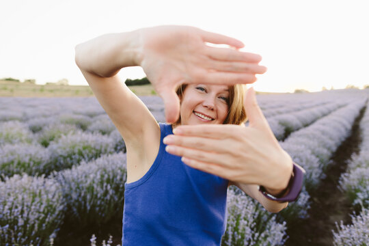 Smiling woman showing finger frame sign in lavender field