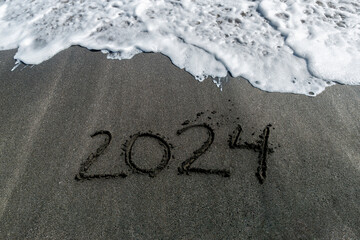 2024 handwritten in black beach sand