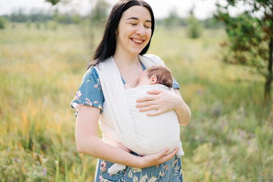Young mother carrying daughter in baby sling