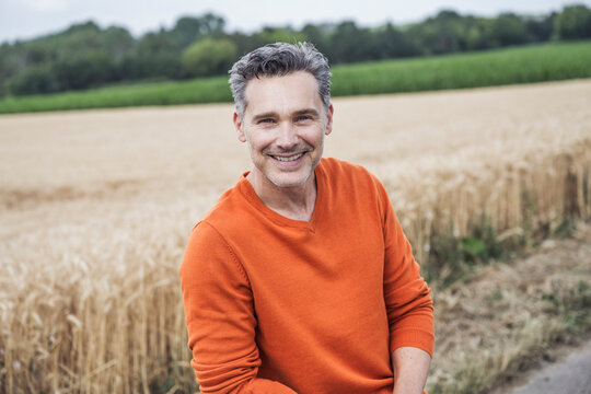Happy mature man in front of field
