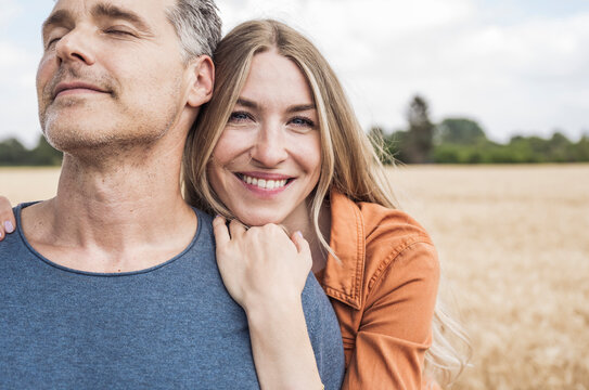 Happy blond woman spending leisure time with man in field
