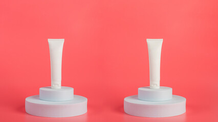 Plastic white tube for cream or lotion. Skin care or sunscreen cosmetic with stylish props on pink background 