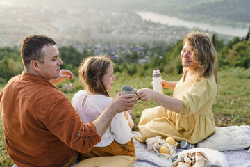Happy woman serving tea to man sitting with daughter