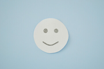 Smiley from white paper on blue background. World Day of Peace. Day Against Humiliation. International Day Of Human Fraternity. International Day of Living Together in Peace