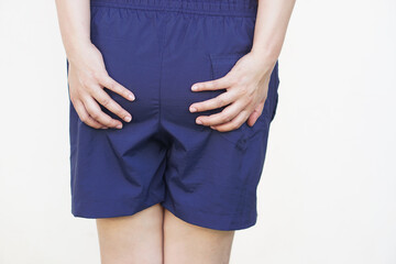Close up woman wears blue shorts, use hands touch her bottom. Concept ,getting hemorrhoids, diarrhea, pain in bottom from long sitting, health problem, healthcare.          