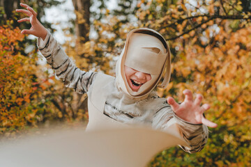 Joyful girl wearing mummy costume and gesturing in garden