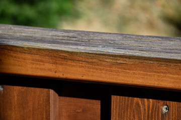 Wooden railing on the terrace outside. Detail on wood. Green landscape in the background