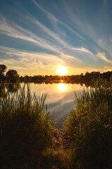 Beautiful colorful sunset over the lake. The sun among the green grass reflecting in the lake. Photo taken in Mojcza, Poland. - 657007149