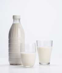 fresh milk in plastic bottle with glass glasses on white background