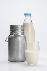 fresh milk in glass bottle with aluminum can and glass cup on white background