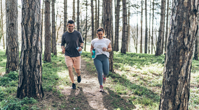 An inspiring scene unfolds as a beautiful, overweight female embarks on a jog in the park with her dedicated partner, embracing their journey to better health