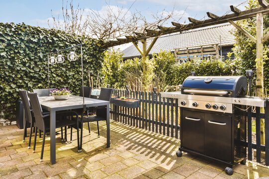 Patio with barbecue grill and chairs around table in backyard