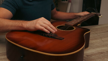 Man changing the strings of a guitar at home. Man's hand are installing or replacing strings on a...