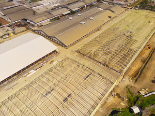 Factory under construction. Aerial drone photo of a factory being built by workers on the edge of...