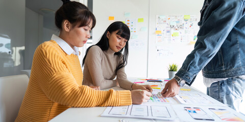 ux developer and ui designer use augmented reality brainstorming about mobile app interface wireframe design on desk at modern office