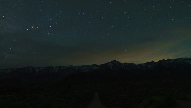 Timelapse day to night of Milky Way to sunrise over scenic dirt road in Alabama Hills in California, USA
