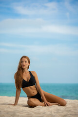 Fototapeta na wymiar Beautiful young woman in black bikini on the beach at sunset.