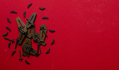Coffin lids in a pile surrounded by bats shot from above on a red background. - obrazy, fototapety, plakaty