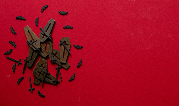 Coffin lids in a pile surrounded by bats shot from above on a red background.