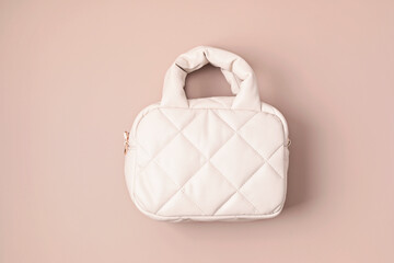 Beige quilted puffed bag on pastel background. Stylish woman handbag. Winter fashion accessories