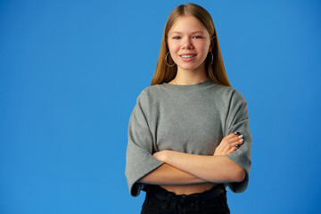 Happy teenager, positive smiling girl on blue background in studio