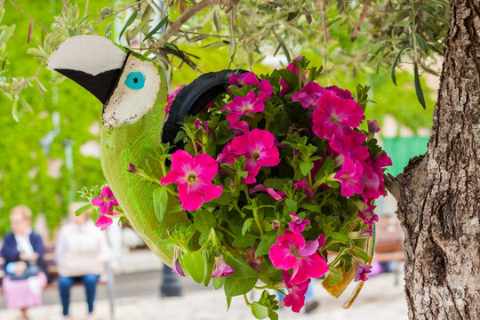 COSTITX, MAJORCA, SPAIN - MAY 1, 2018: Green parrot flower decoration made with a car tire and pink petunias on "Costitx en Flor" (Costitx in bloom) Flower Fair, Majorca, Spain
