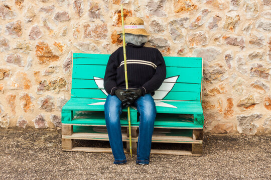 Man dummy, representing a farmer or a fisherman, sitting on the bench with a stone wall in the background on "Costitx en Flor" (Costitx in bloom) Flower Fair, Majorca, Spain