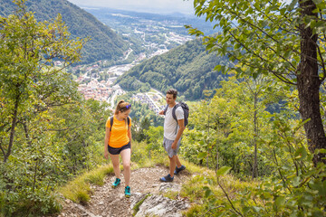 Hiking couple walking uphill along a forest trail, enjoying outdoor activity on a sunny summer day. Nature and recreation concepts.