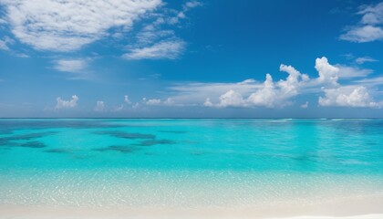Obraz premium Sandy beach on sunny day with white sand and rolling calm wave of turquoise ocean, white clouds in blue sky background