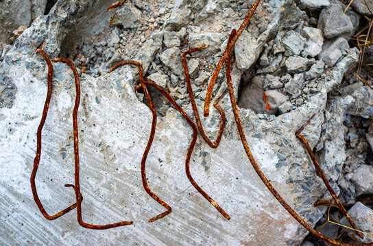 On an abandoned construction site, rusty iron wires are exposed inside a broken cement precast slab.
