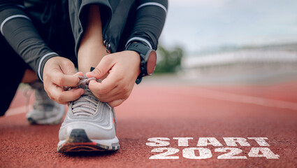 Athletes are getting ready to run on the track with text Start 2024 in New Year's start concept. - obrazy, fototapety, plakaty