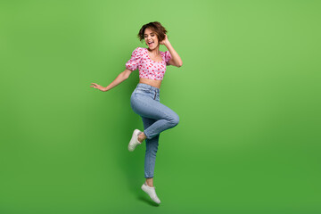 Full size photo of pretty young girl jump dance energetic wear trendy pink cherry print outfit isolated on green color background