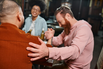 blurred african american woman smiling near men shaking hands while sitting in pub after work