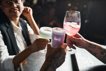 happy african american woman clinking glasses with tattooed men while resting in bar after work