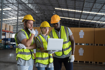 Group of male and female warehouse worker working and discussing together with laptop computer in industry storage warehouse