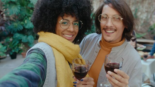 Happy Latin couple standing together in the backyard on autumn day, smiling and posing for camera with red wine during barbecue party. POV shot, video portrait