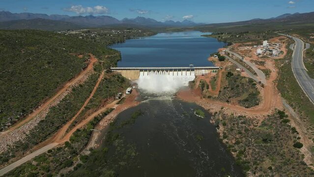 High aerial forward flight toward Clanwilliam Dam wall on Olifants River, water flows through all sluice gates