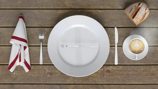 An empty dinner plate on a wooden table with a knife and fork rotating on the plate like the hands of a clock alongside a serviette, a cappuccino, and some homemade brown bread.