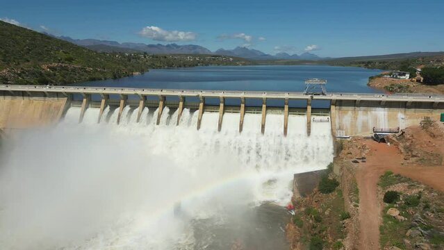 Rotate around Clanwilliam Dam wall, water gushes through sluices, rainbow in mist spray