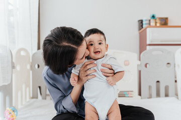 Happiness Asian mother conference and playing with adorable her son looking at camera. Asian mom lifting and playing newborn baby. Happy asian family healthcare love together mother’s day concept.
