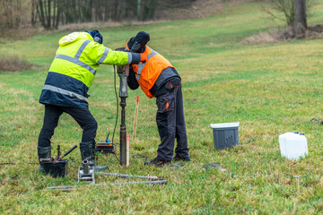 Workers using a soil sampling drill to get a core sample of the ground on a future construction...