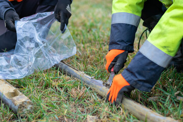 Worker collects soil sample from core drill and putting it to plastic bag, closeup side view