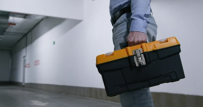 Close-up, a locksmith appears in the video with tools on his belt and a suitcase.