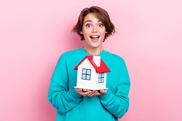 Portrait of astonished cute girl wear trendy teal clothes hands hold house rejoice moving new apartment isolated on pink color background